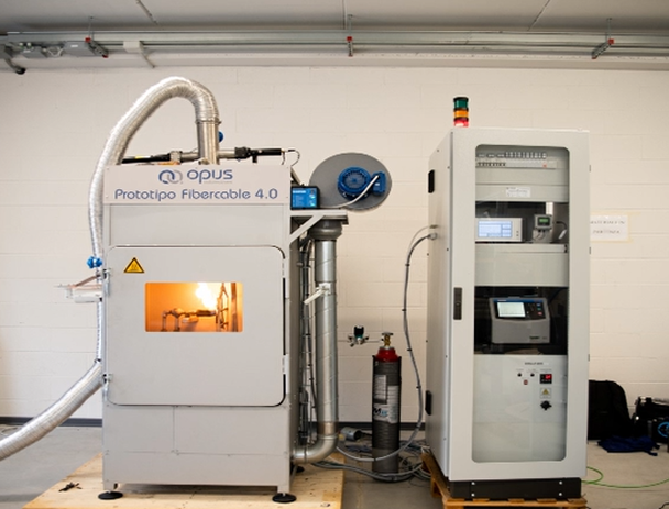Prototipo sperimentale FiberCable 4.0 per la produzione di cavi in fibra ottica con guaina termoplastica innovativa, dotato di camera di lavorazione e sistema di controllo avanzato