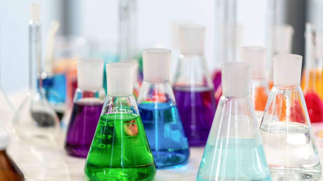 Provette con soluzioni chimiche colorate su banco da laboratorio