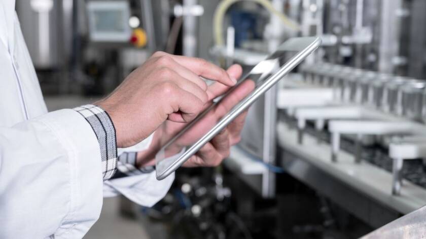 Un operatore che con il tablet gestisce una linea di produzione industriale
