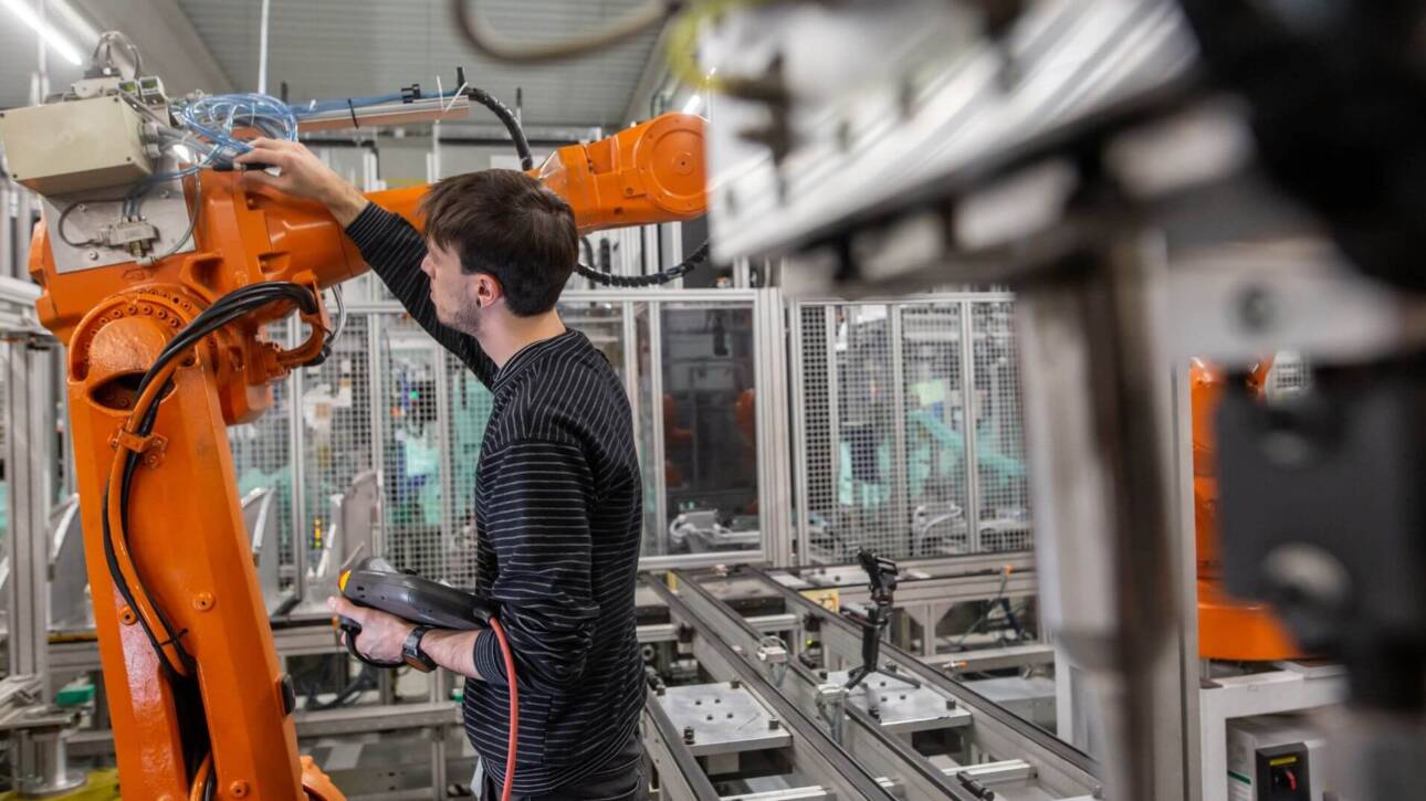 Operaio con HMI che controlla il funzionamento di un robot industriale